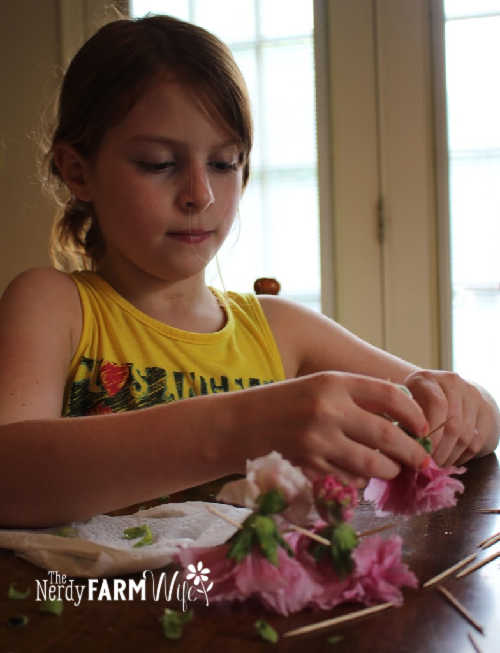 girl with red hair and yellow shirt making old-fashioned dolls from hollyhock flowers