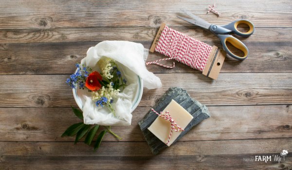 A wooden table with soap, string, and flowers