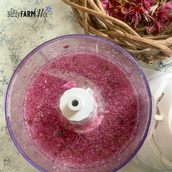 peach flowers and glycerine blended together in a mini food processor on a gray and cream background