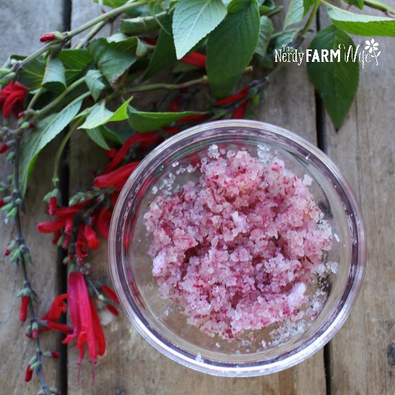 bowl of body scrub surrounded by fresh flowers