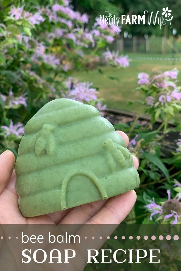 woman's hand holding bar of beehive shaped soap in front of bee balm flowers