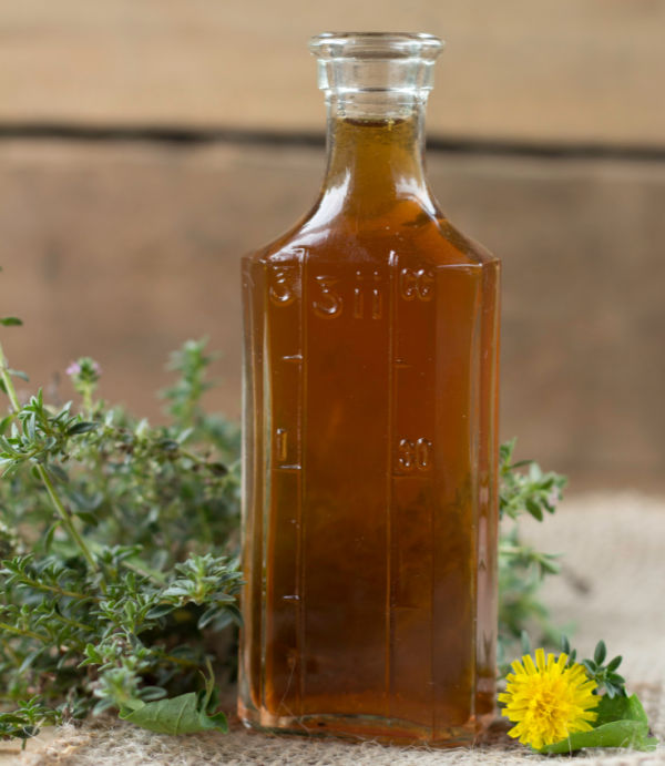 bottle of vinegar with fresh thyme and dandelion flower