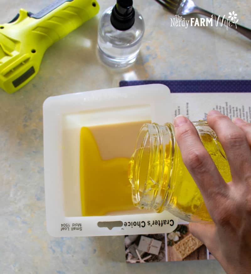 pouring a layer of saffron colored melted soap base over a layer of oatmeal base
