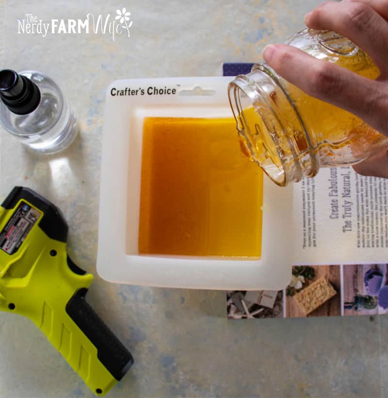 Pouring natural orange colored soap base into the mold