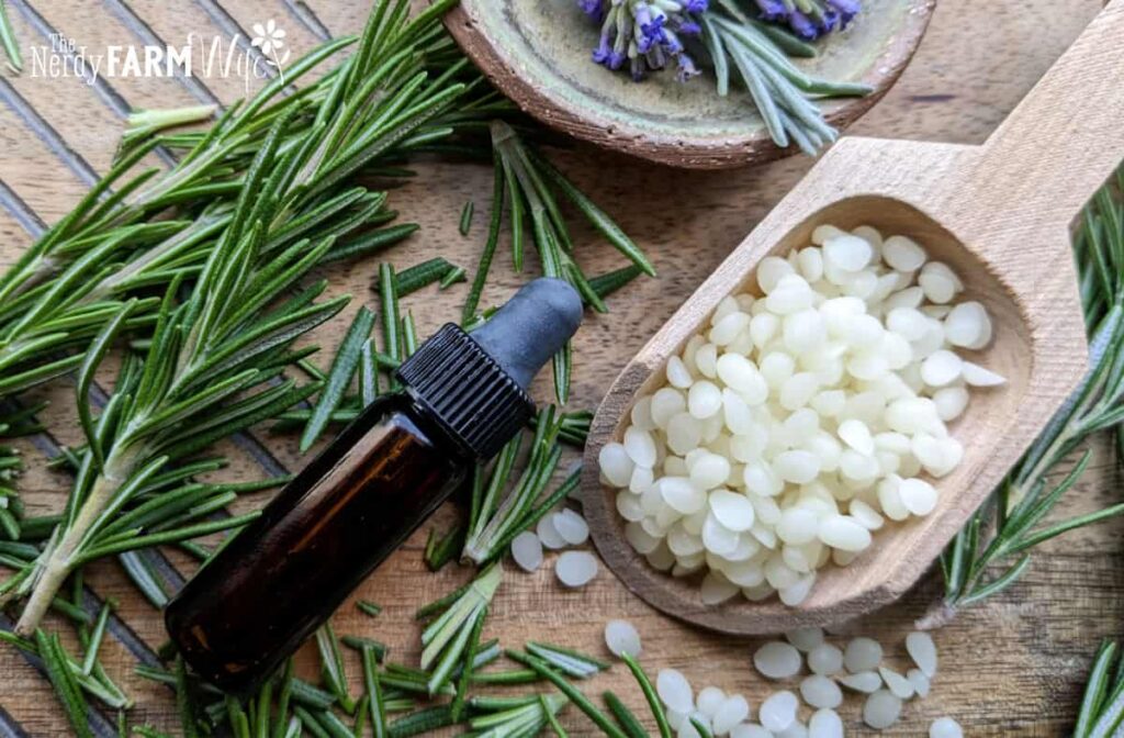small bottle of essential oil with beeswax and herbs on a wooden background