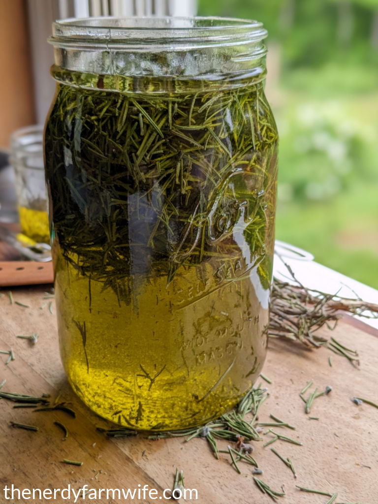 jar of rosemary oil with rosemary leaves floating inside.